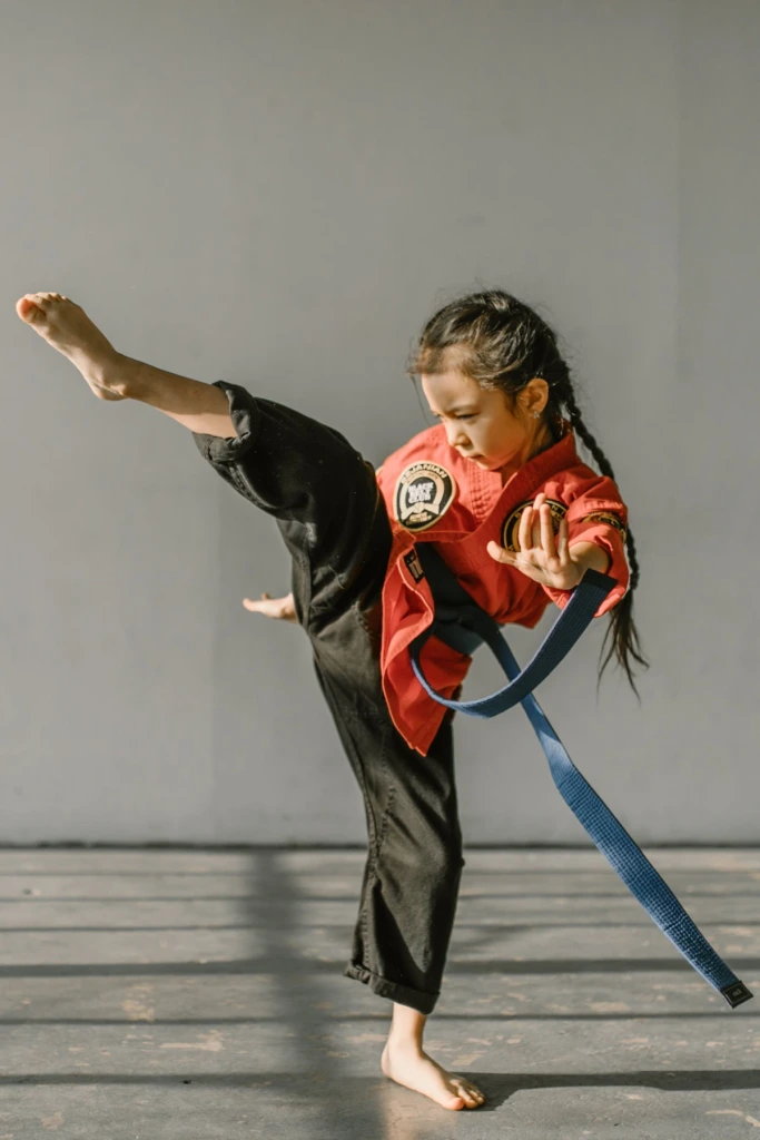 Jeune pratiquante d’arts martiaux exécutant un coup de pied haut