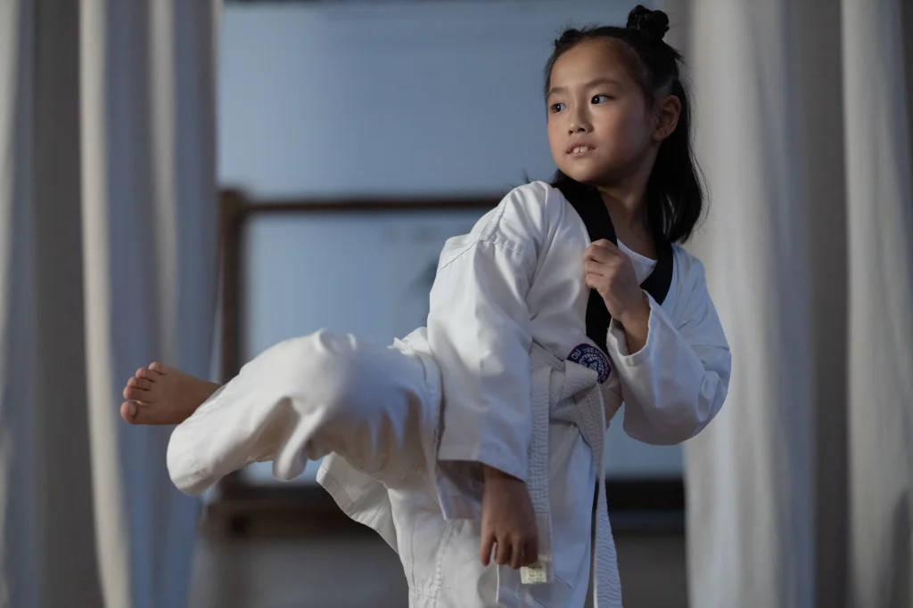 Jeune élève en dobok blanc qui pratique un coup de pied de taekwondo